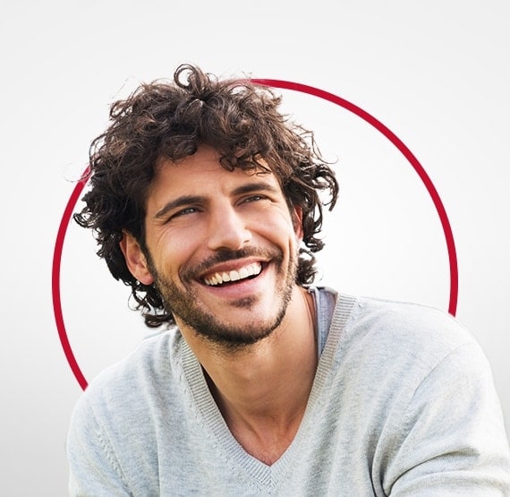 Насмеан млад човек во сив џемпер, среќен по лекувањето кандидијаза со Канестен®